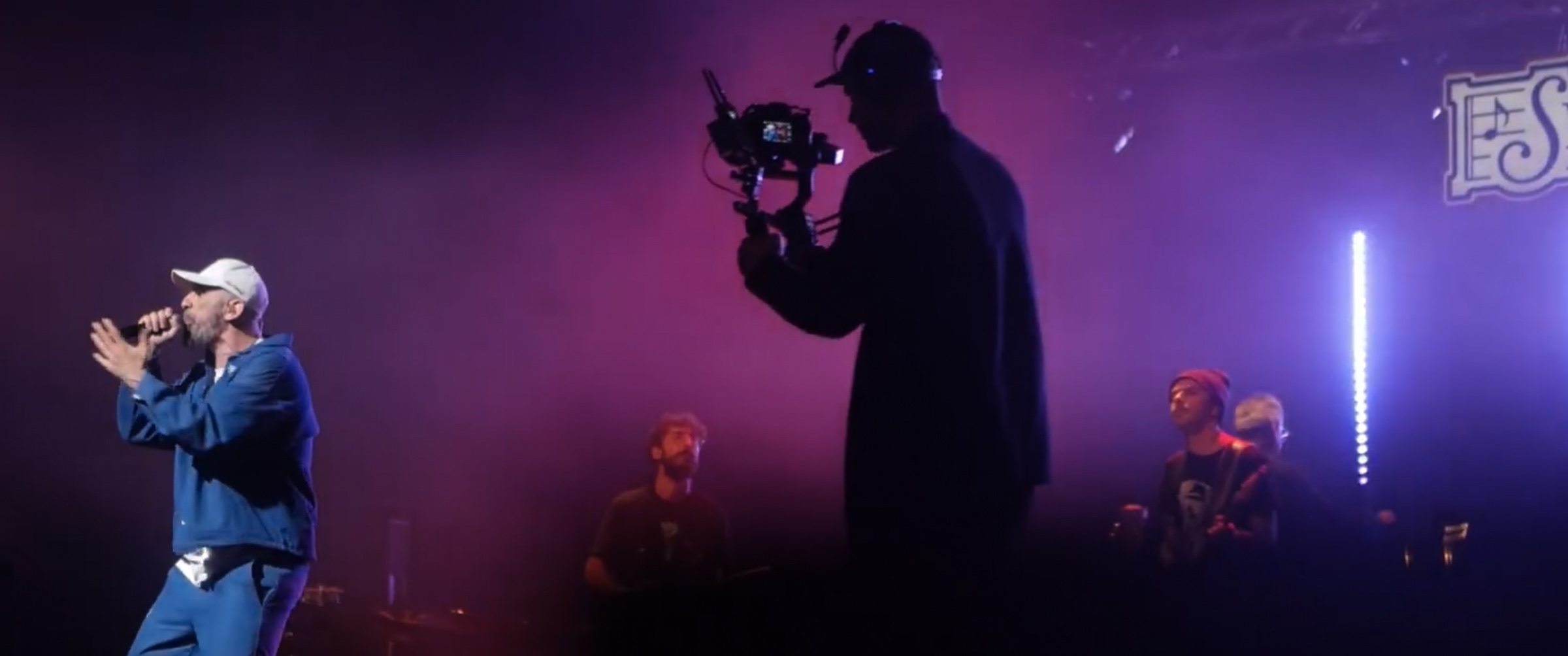 Eirinaios Papacharisis filming a live concert on a gimbal, in silhouette against stage light
